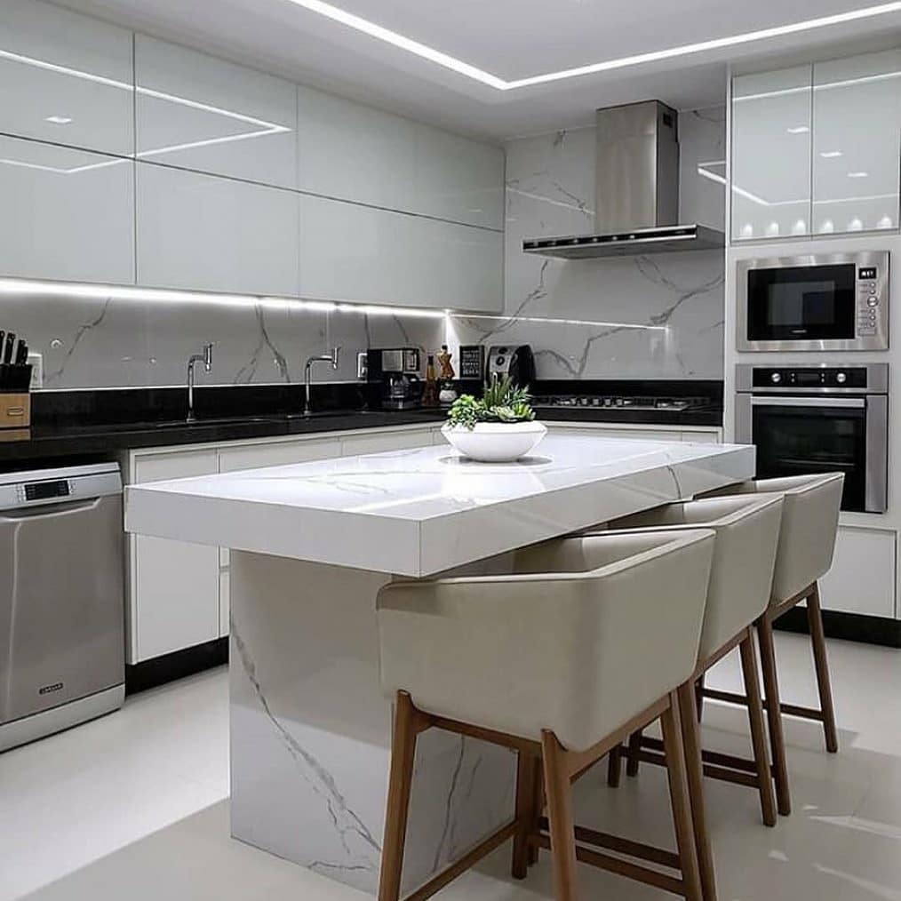Nesta cozinha moderna e convidativa dominam o branco e o marmorizado.