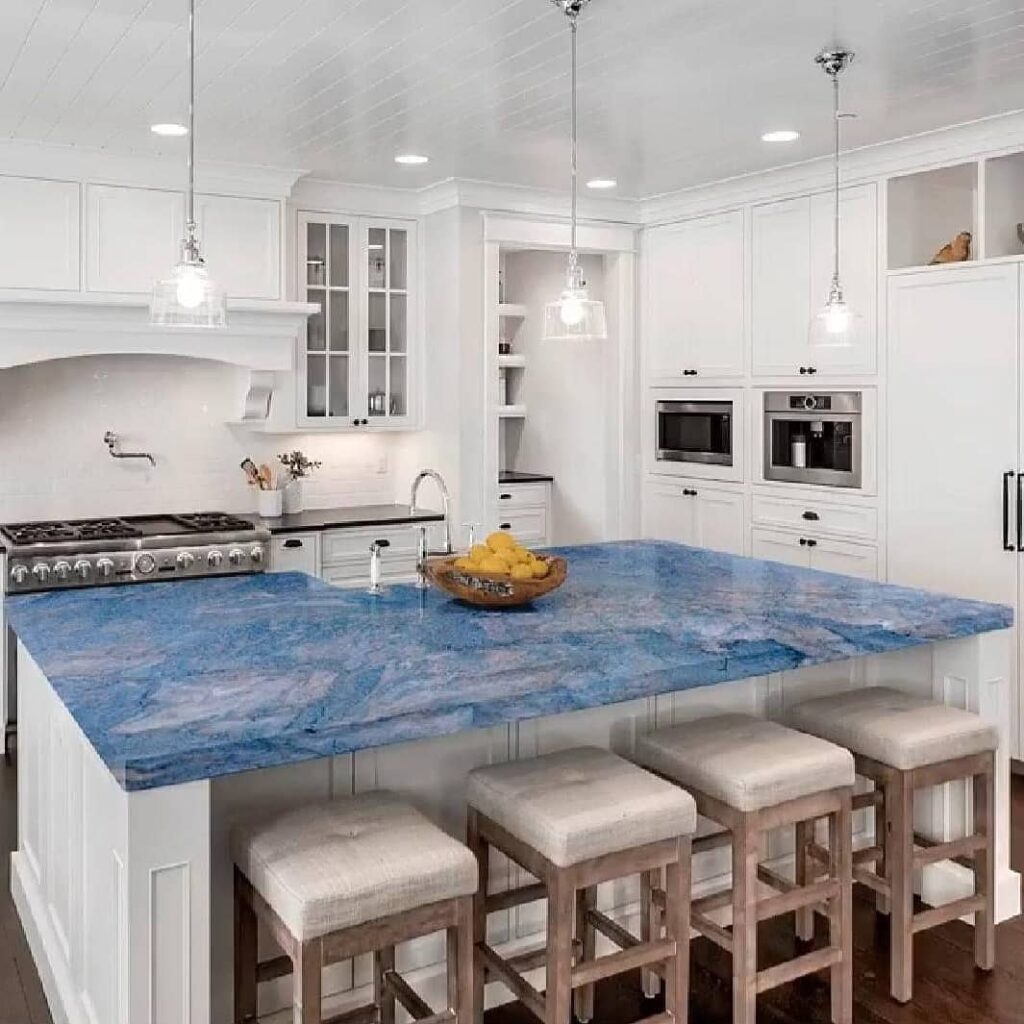 Cozinha clean em branco com toque original dado pela mesa em granito azul