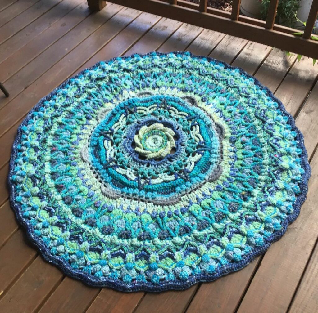 Tapete de crochê para cozinha redondo em tons de azul e com flor no meio